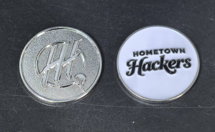 Set of premium golf ball markers featuring Hometown Hackers logo on silver and white backgrounds